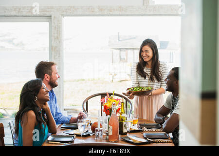 Woman serving friends at dinner party Stock Photo