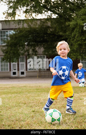 Caucasian boy playing soccer in field Stock Photo