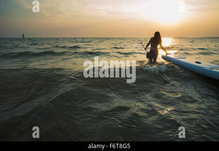 Woman pulling paddleboard in lake Stock Photo