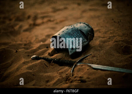 Medieval helmet and sword in sand Stock Photo