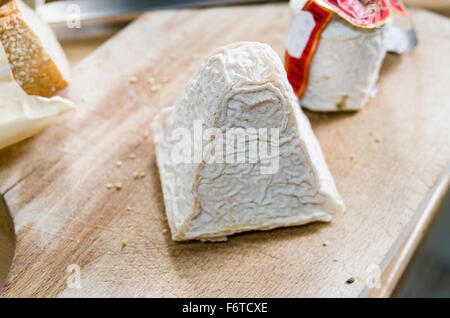 The Wrinkled Rind of a piece of Pouligny St Pierre cheese. A block of cheese on a wooden cutting board. Stock Photo