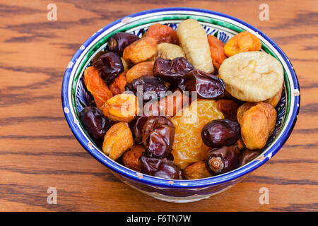 Central Asian dried fruits in traditional ceramic bowl on wooden table Stock Photo
