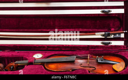 old wooden violin with bow in red velvet case Stock Photo