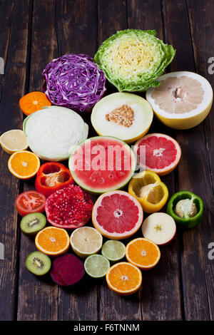 Halves of different vegetables and fruits on dark wood Stock Photo