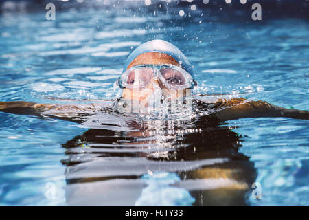 Female triathlet with goggles bubbling out of water in swimming pool Stock Photo