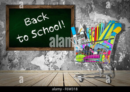 office / school supplies in shopping cart in front of classroom with blackboard Stock Photo