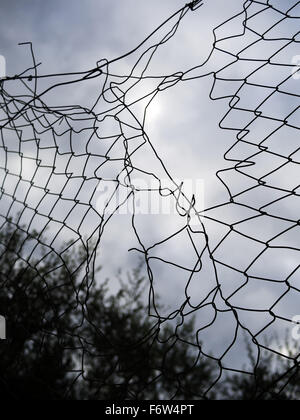 Patched up hole in mesh wire fence Stock Photo
