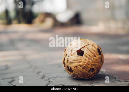 Sepak Takraw ball on pavement tiled bricks with copy space, background blurred. South East Asia famous local sport or Asian activities concept Stock Photo