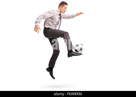 Full length profile shot of a young businessman playing football shot in mid-air isolated on white background Stock Photo