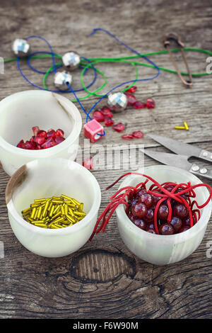 Buttons,threads and beads on wooden countertop on the background box with accessories Stock Photo