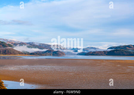 A view looking up the Mawddach estuary at low tide with sand banks in the foreground with rising mists on the background hills. Stock Photo