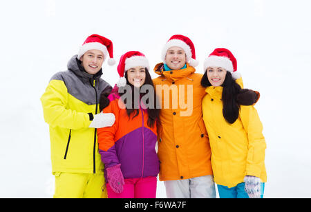 happy friends in santa hats and ski suits outdoors Stock Photo