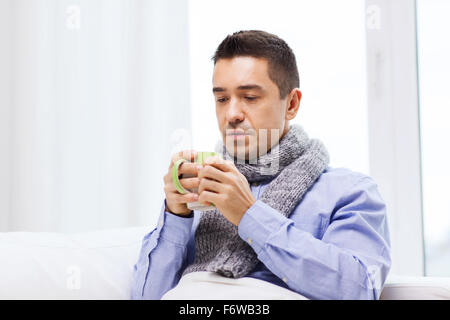 ill man with flu drinking hot tea from cup at home Stock Photo