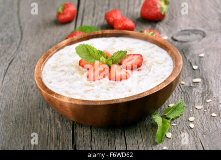 Oats porridge with fresh strawberry in wooden bowl Stock Photo