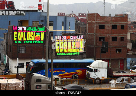 Banners promoting Halloween parties on brick buildings next to busy Av Panamericana Norte highway, Rimac district, Lima, Peru Stock Photo