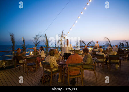 Passengers enjoying drinks on the deck of cruise ship MS Delphin  Passat Kreuzfahrten  at dusk, Caribbean Sea Stock Photo