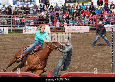 Cowboy trying to get on racing horse at the local rodeo rescue racing competition Stock Photo