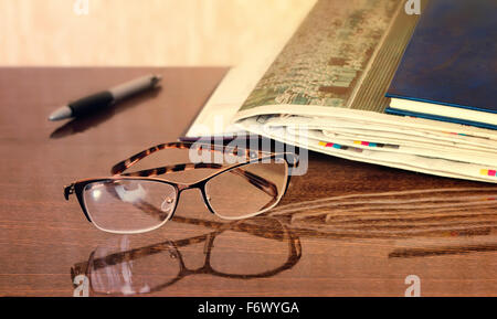 On the table are glasses, close books, magazines, Newspapers. Stock Photo