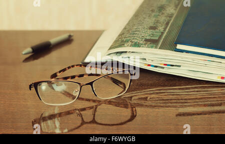 On the table are glasses, close books, magazines, Newspapers. Stock Photo