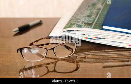 On the table are glasses, close books, magazines, Newspapers. Stock Photo
