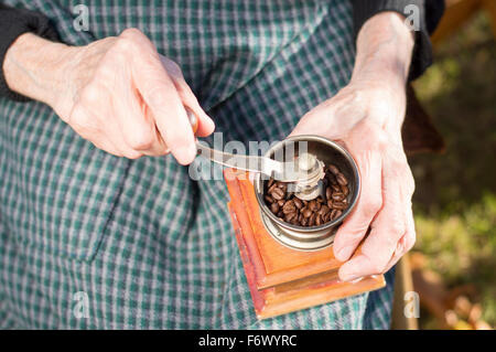 Old hands grinding coffee on a vintage wooden coffee grinder Stock Photo