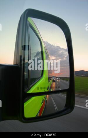 Highway traffic with headlights and sunset in a rear view mirror of an emergency vehicle Stock Photo