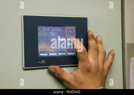 A male hand operating an electric control panel screen, in an electric power plant, St. Paul Island, Southwestern Alaska, USA, Summer Stock Photo