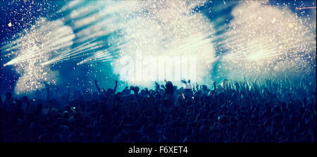 Cheering crowd at concert in front of stage with pyrotechnics Stock Photo