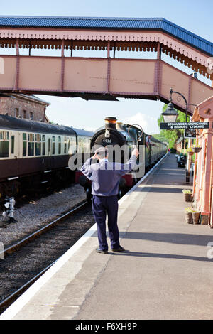 The signalman exchanges a single line token with the fireman of steam train at Williton station on the West Somerset Railway, En Stock Photo