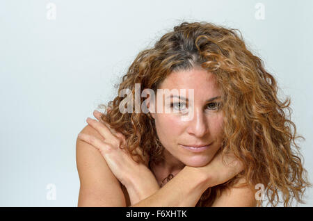 Close up Young Blond Woman withe Curls Staring at the Camera Against Gray Background with Copy Space. Stock Photo