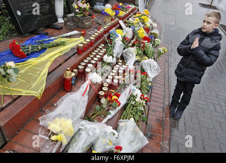Kiev, Ukraine. 21st Nov, 2015. A boy pray in front the memorial to victims of anti-government protests on Maidan on the street Institutska, during the second anniversary of the Euromaidan Revolution in Kiev, Ukraine, 21 November 2015. On 21 November 2013 activists started an anti-government protest after then-Prime Minister Mykola Azarov announced the suspension of a landmark treaty with the European Union. The eventually led to the ouster of President Viktor Yanukovych, creating political rifts through the country that erupted into violent conflict between separatists and government forces i Stock Photo