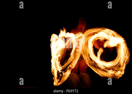 Native Hawaiian fire dancer spinning lit batons at night at a luau in Hawaii Stock Photo