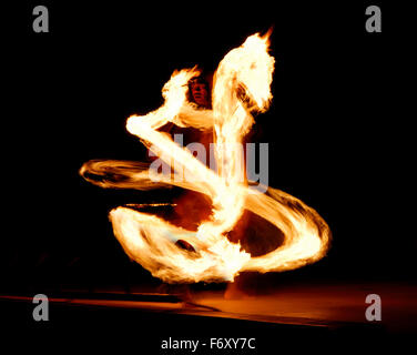 Luau fire dancer stage performance at night with flaming baton looks like fire dragon Maui Hawaii Stock Photo
