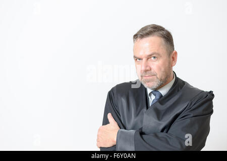 Confident businessman standing with folded arms and a serious expression giving the camera a penetrating speculative look, head Stock Photo