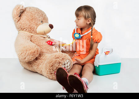 Baby is playing doctor, treats a bear Stock Photo
