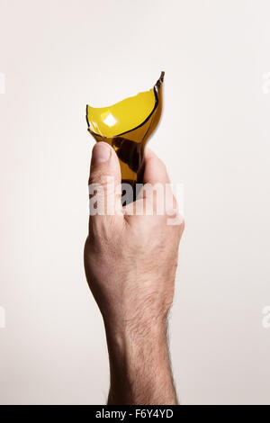 shot from above of a man's hand holding a broken glass bottlen in a threatening way Stock Photo