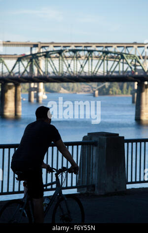 A cyclist bikes along the waterfront in Portland, Oregon. Stock Photo