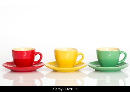 Red, yellow and green espresso cups with saucers.  Isolated on white background with reflection and copy space Stock Photo