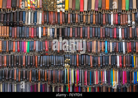 Many colored leather belts on a market. Fashion background Stock Photo