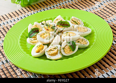 Boiled quail eggs halves on a green plate Stock Photo