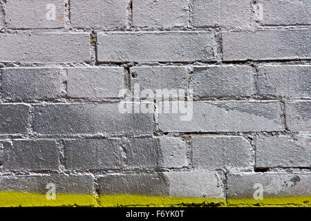Silver painted graffiti brickwall with some yellow Stock Photo
