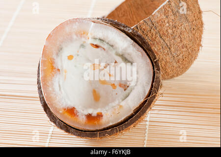 Rotten half coconut copra, opened seed interior, mature moldy and rotten nut bad food wastage, halved coconut shells garbage... Stock Photo