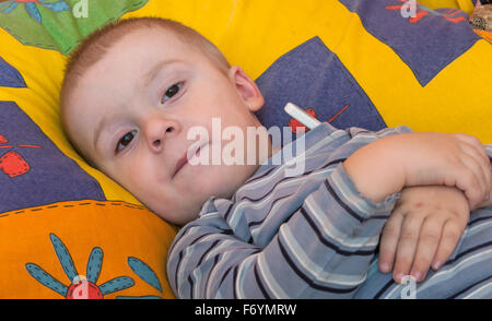sick little boy in bed. Measuring of temperature Stock Photo