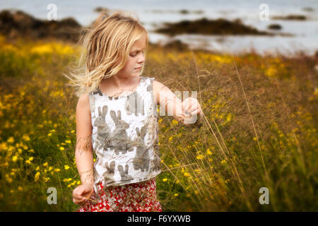 Girl playing in field of reeds and flowers