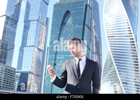 Businessman using smartphone on skyscraper background Stock Photo