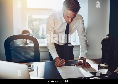 Business man standing at desk working on documents, white shirt and tie, male executive