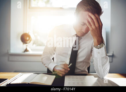 Business man working concentrated on documents looking tired holding his hand to his forehead Stock Photo