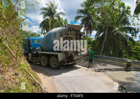 DONSOL, PHILIPPINES - JUNE 2, 2015: Unknown road workers with a cement truck building a new forest road in the philippines Stock Photo