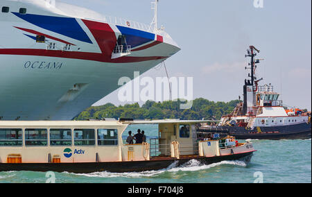 Tugboat leading a cruise liner into the San Marco canal as a vaporetto waterbus passes Venice Veneto Italy Europe Stock Photo
