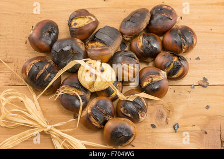 Heart shaped pile of freshly baked chestnuts on the wooden table